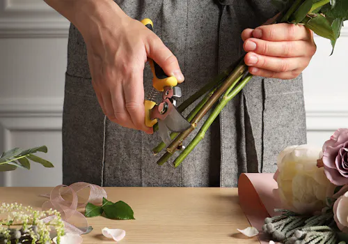 A male pair of hands carefully trims the stems of a flower grouping