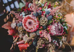 Autumn colors abound in this purple, blue and brown floral arrangement