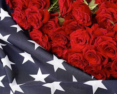 Red rose arrangement draped with American flag fabric for patriotic Fourth of July floral d&eacute;cor