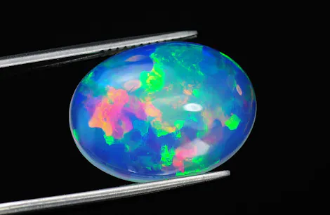 A vibrant, multi-colored opal gemstone, held by silver tweezers against a black background, displays hues of blue, green, pink, and yellow.